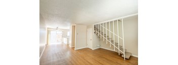 an empty living room with a staircase leading up to a loft