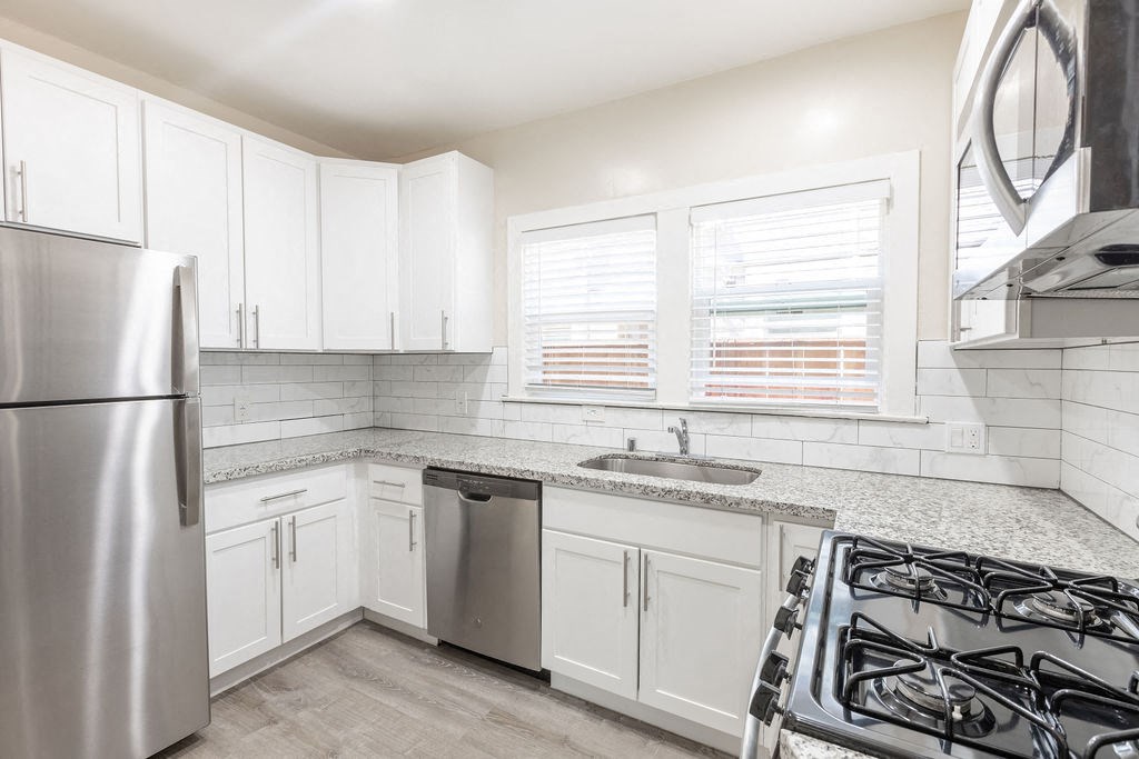 a kitchen with white cabinets and a stainless steel refrigerator