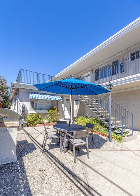 a patio with a table and umbrella in front of a building