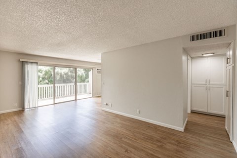 the living room and dining room with wood flooring and a balcony