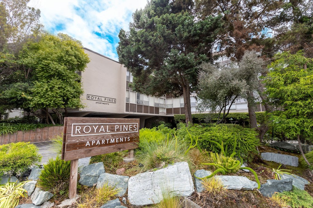 A sign for Royal Pines Apartments is in front of a building.