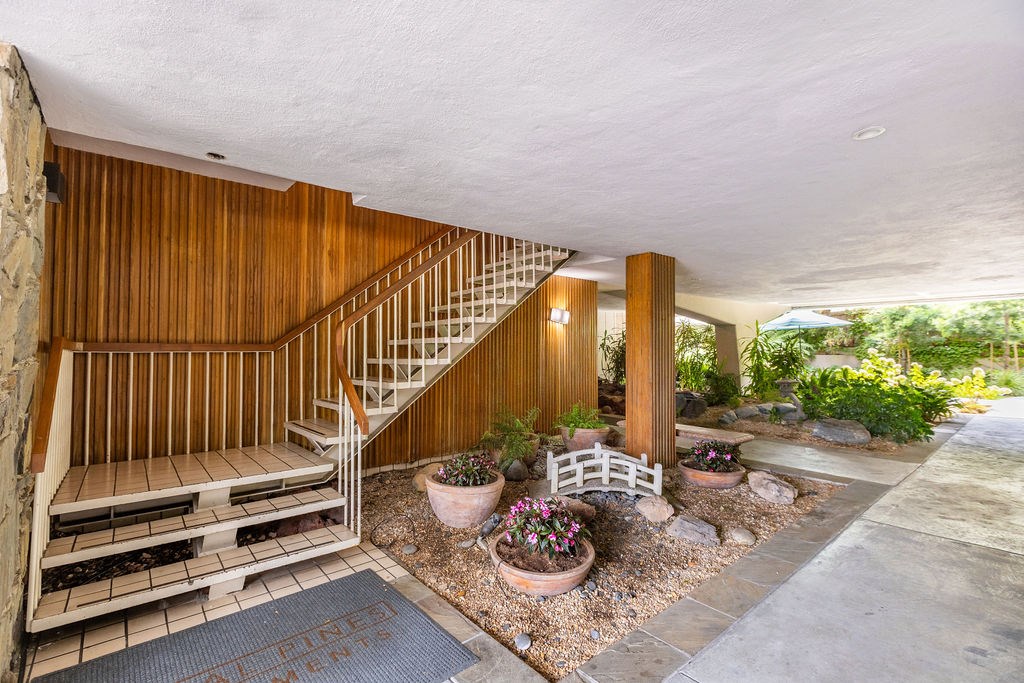 A wooden staircase with a metal railing leads up to a landing with a white fence.