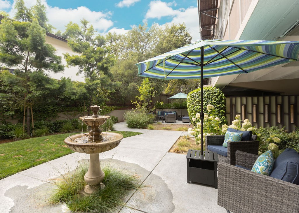 A patio with a fountain and a wicker sofa.