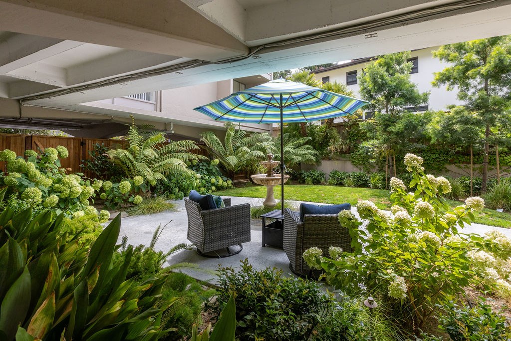 A patio with a blue umbrella and two chairs.