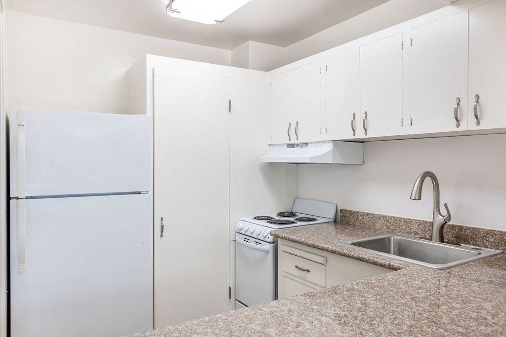 A kitchen with a white refrigerator, a washing machine, a dishwasher, and a sink.