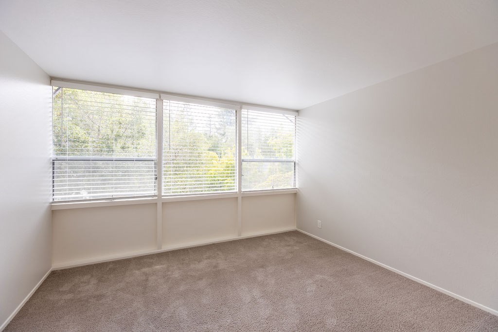 A room with a window covered by white blinds.