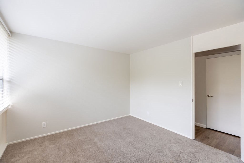 A room with a carpeted floor and a door on the right side.