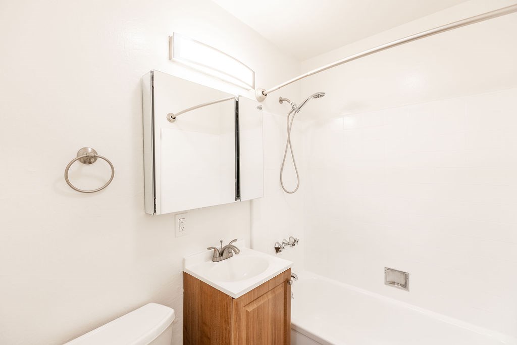 A white bathroom with a toilet, sink, and mirror.