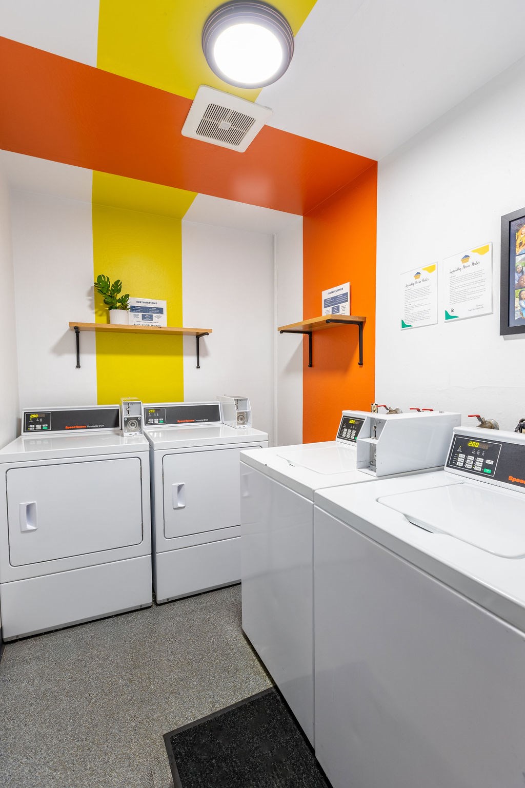 A laundromat with orange and yellow walls and white machines.