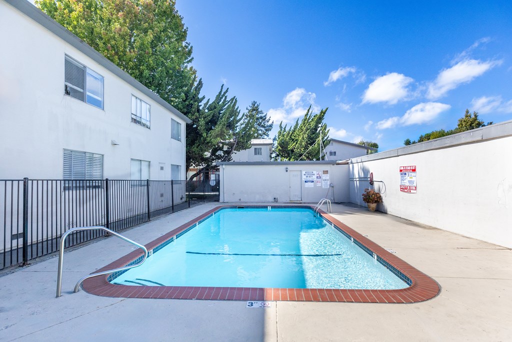 A small pool in a backyard surrounded by a black fence.