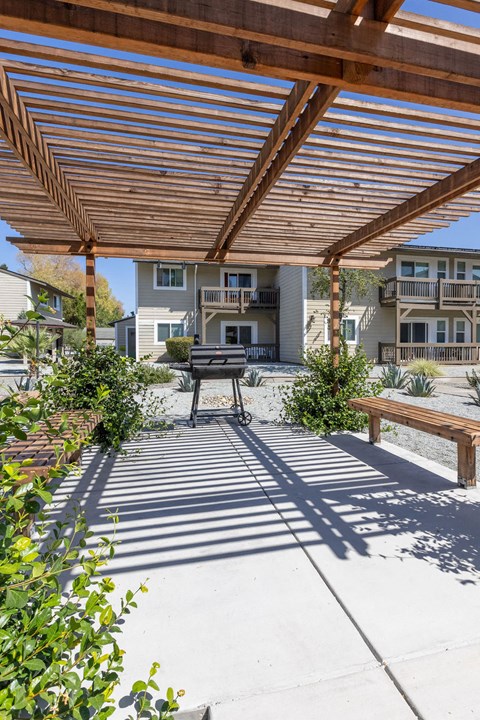 a covered patio with a picnic table and a grill