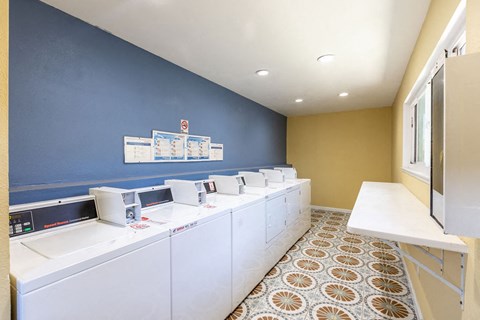 a laundry room with a row of washers and dryers