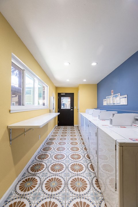 a laundry room with blue and yellow walls and a tile floor