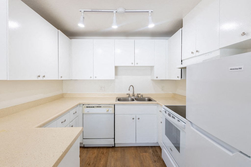 a kitchen with white cabinets and appliances and a sink