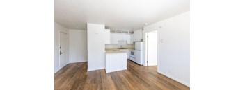 an empty kitchen with white cabinets and a wood floor