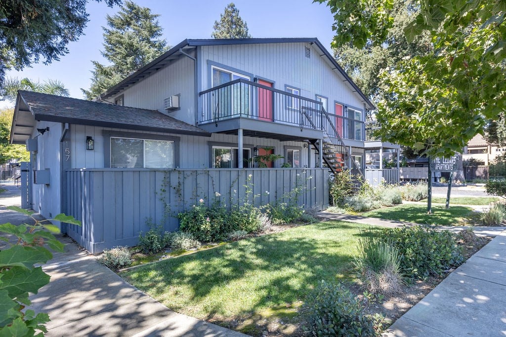 the front of a blue house with a yard and a deck