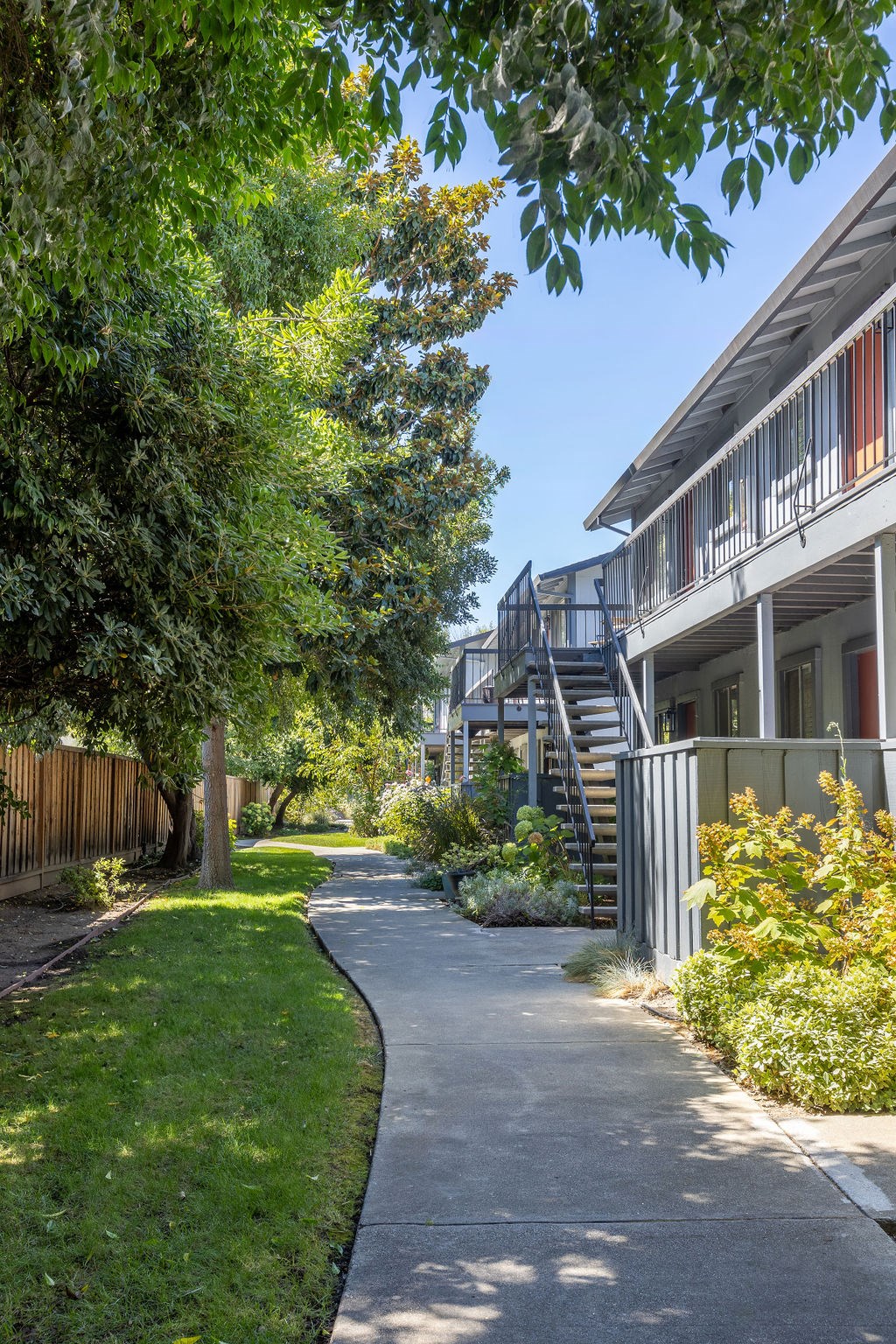a sidewalk in front of a building with trees and grass
