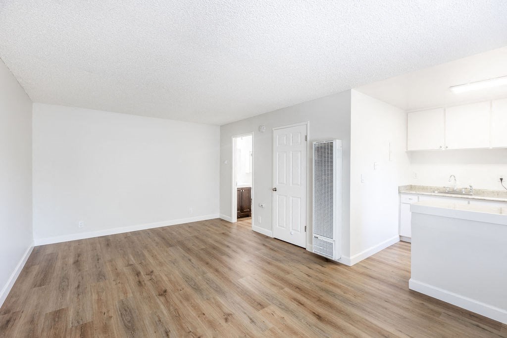 an empty living room and kitchen with white walls and wood floors