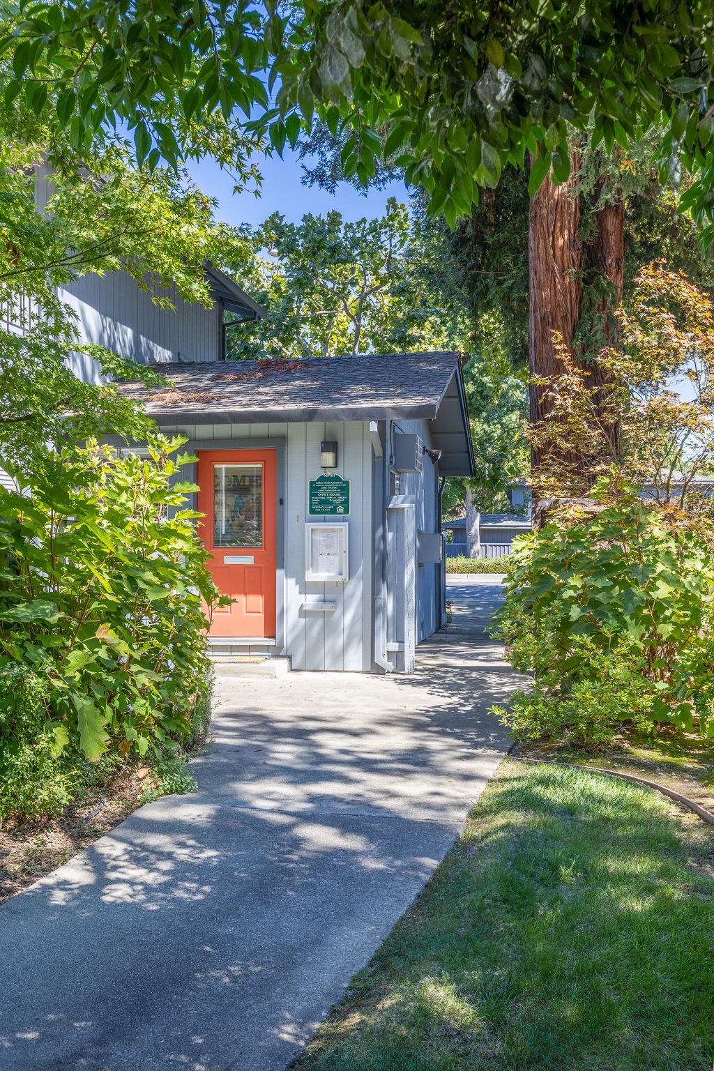 a small building with a red door and a sidewalk