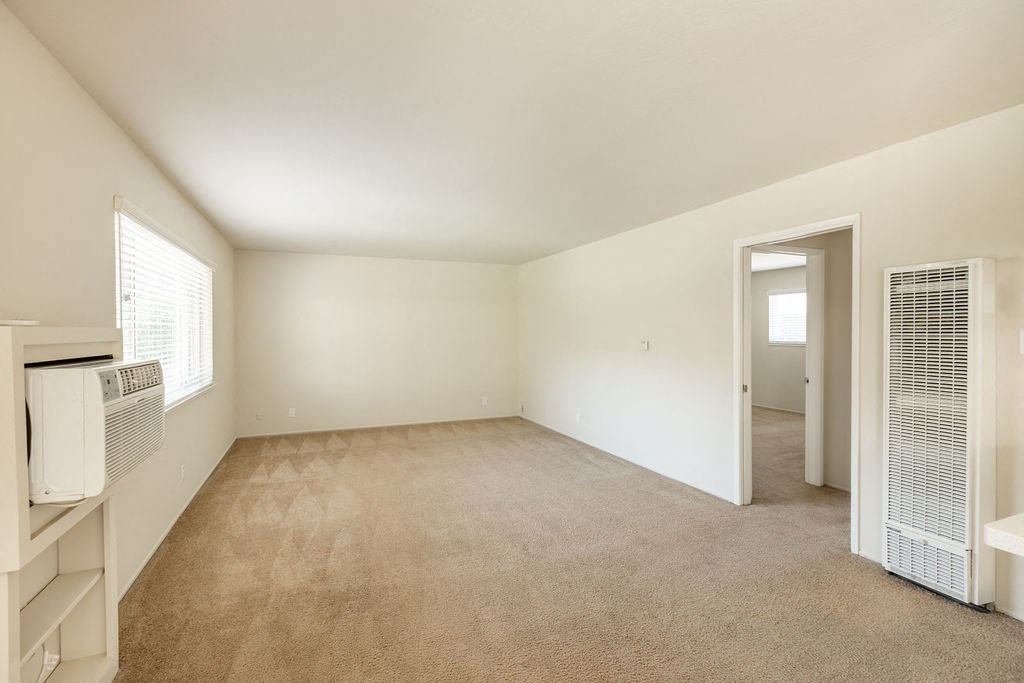 an empty living room with an open door to a hallway and a bedroom with a