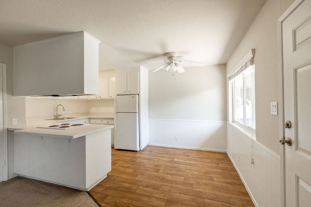 an empty kitchen with white cabinets and a white refrigerator