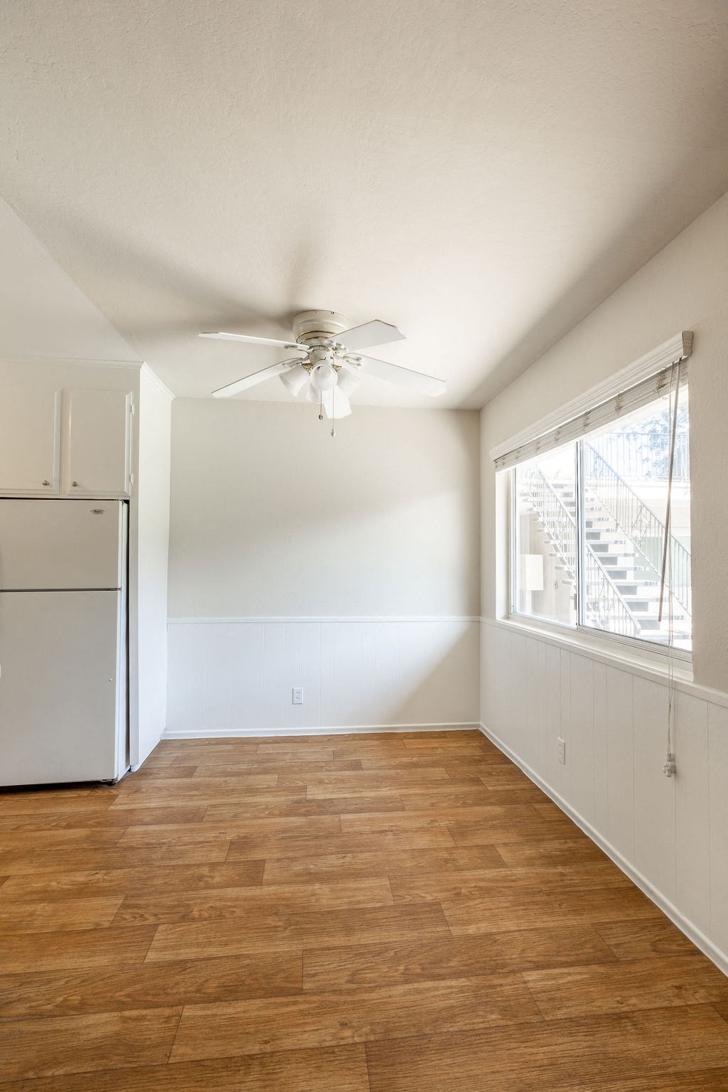 an empty living room with a ceiling fan and a window