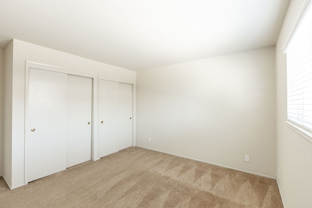 a bedroom with a carpeted floor and white closet doors