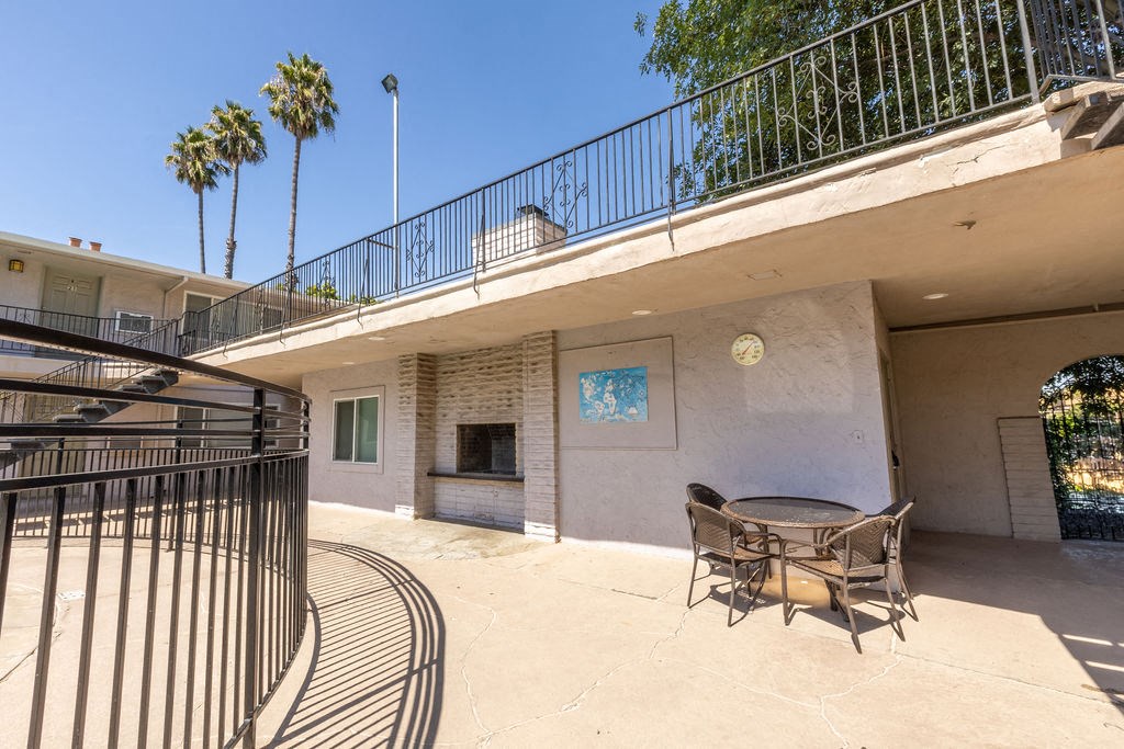 a patio with a table and chairs and a balcony