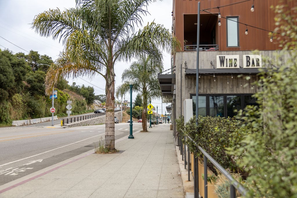 a sidewalk in front of a building with palm trees