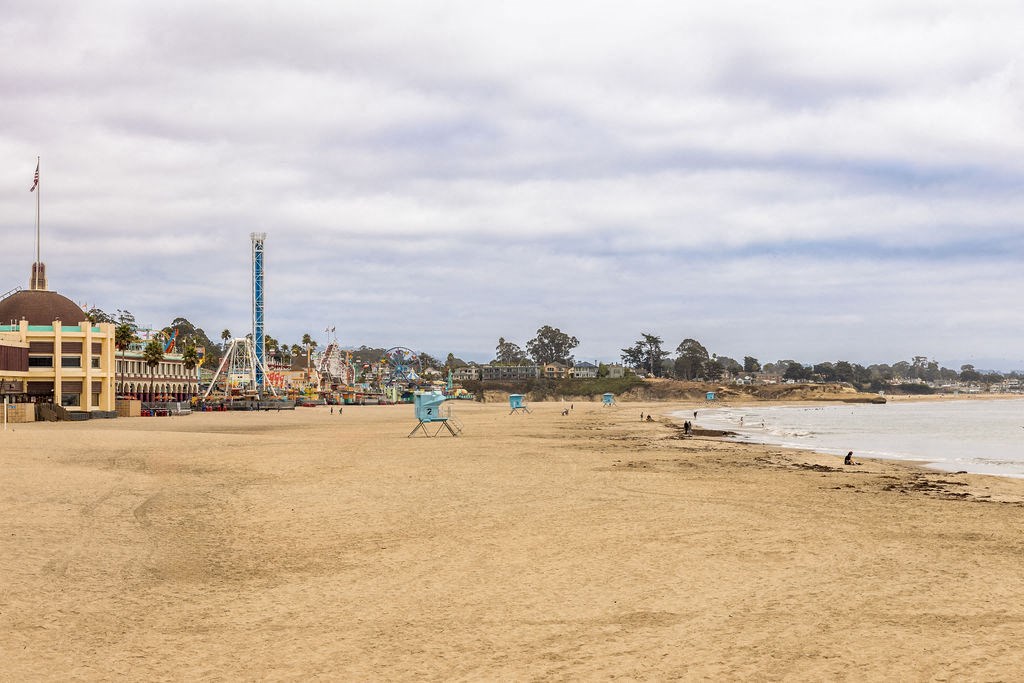 people walking on the beach near a amusement park