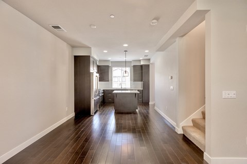 a living room and kitchen with wood floors and white walls