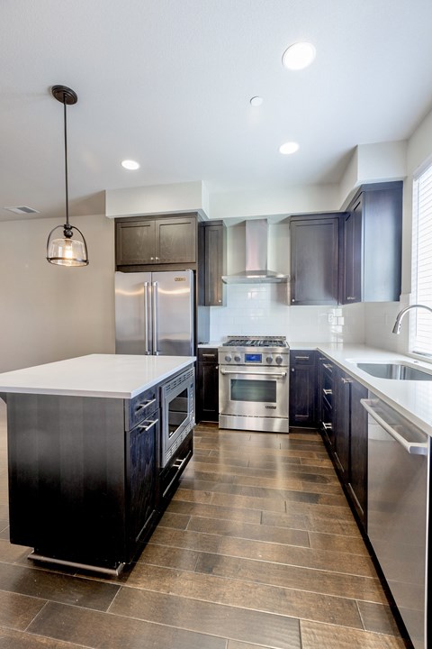 A modern kitchen with dark wood cabinets and stainless steel appliances.