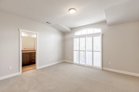 A spacious room with a large window and a carpeted floor.
