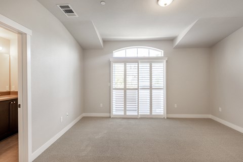 an empty living room with a large window and blinds