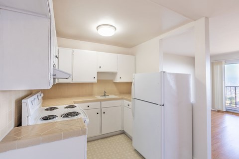 A white kitchen with a stove top oven and a refrigerator.