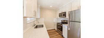 A kitchen with a stainless steel refrigerator, oven, and sink.