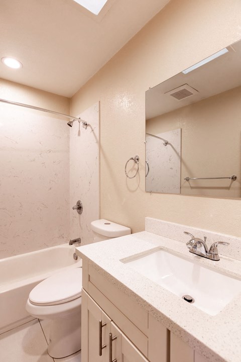 A white bathroom with a toilet, sink, and bathtub.