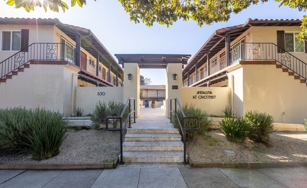A sunny day at the entrance of a residential area with a staircase leading to a building.