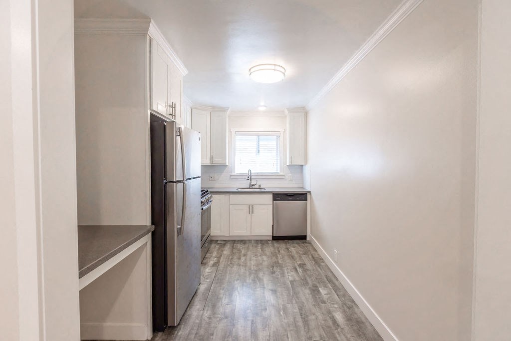 A kitchen with white cabinets and a stainless steel refrigerator.