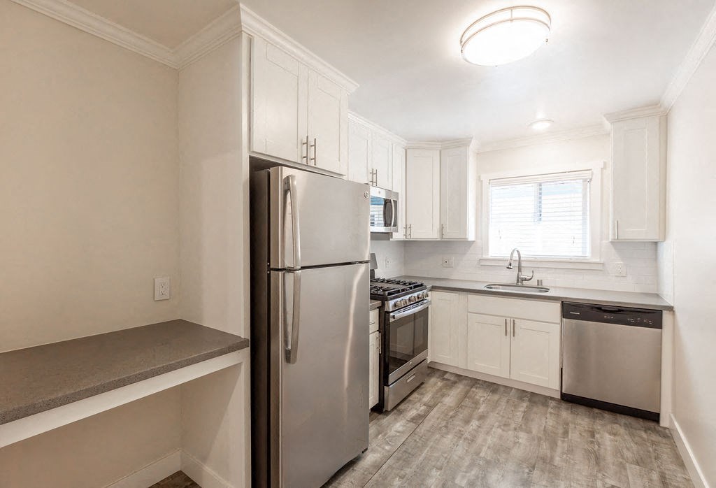 A kitchen with a refrigerator, oven, and microwave.