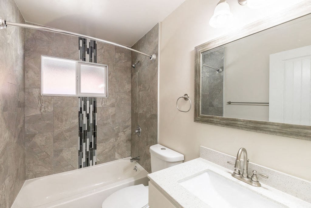 A bathroom with a white sink, a white toilet, a bathtub, and a mirror.