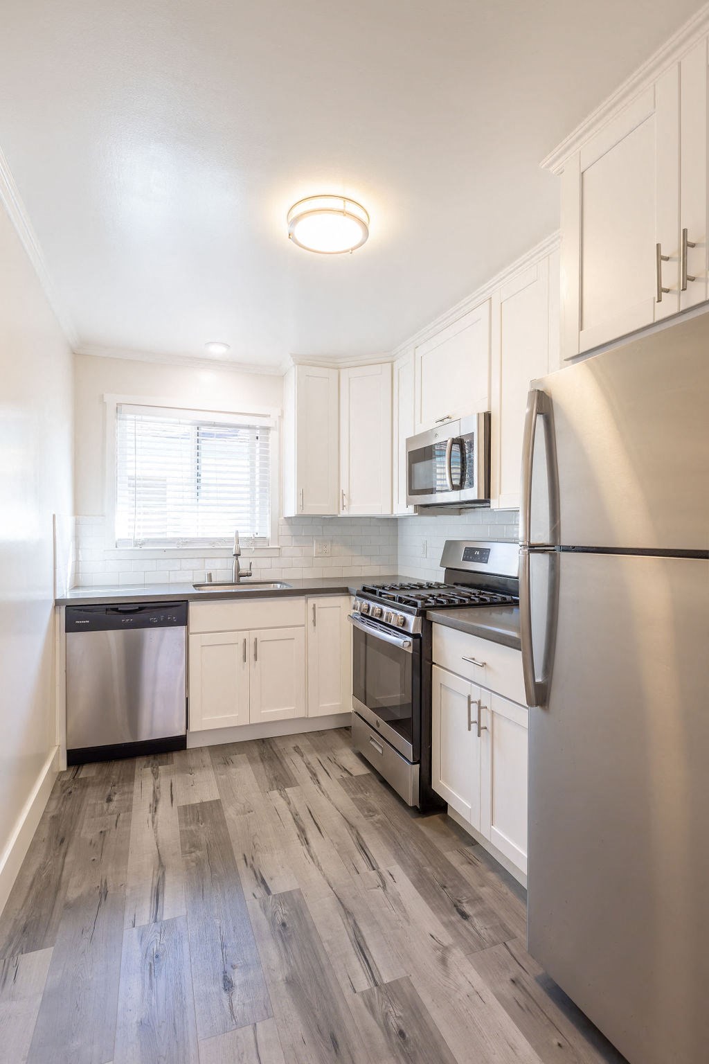 A kitchen with a stainless steel refrigerator, microwave, and oven.