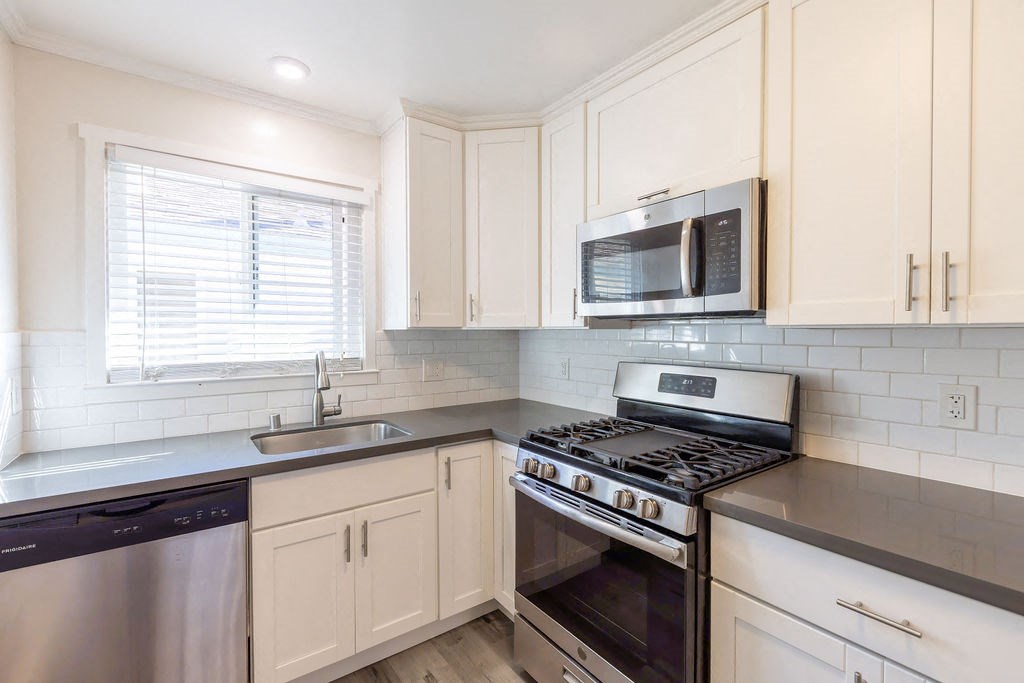 A kitchen with a stove, dishwasher, and microwave.