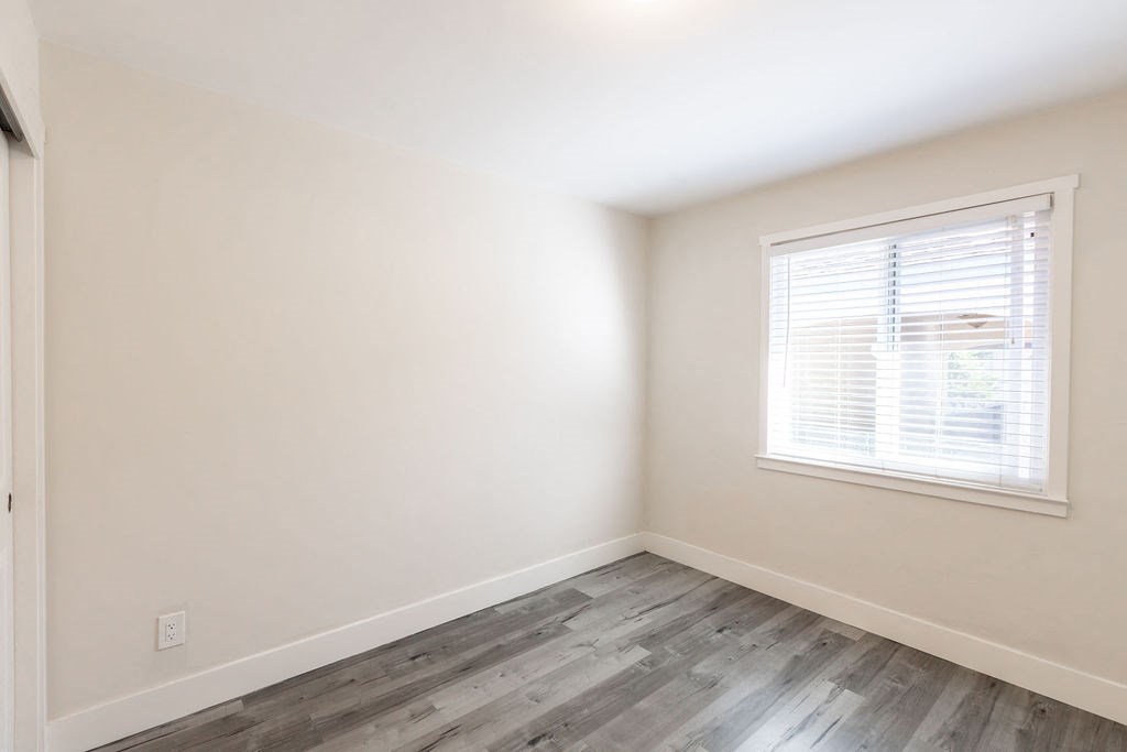 A room with a window and wooden flooring.