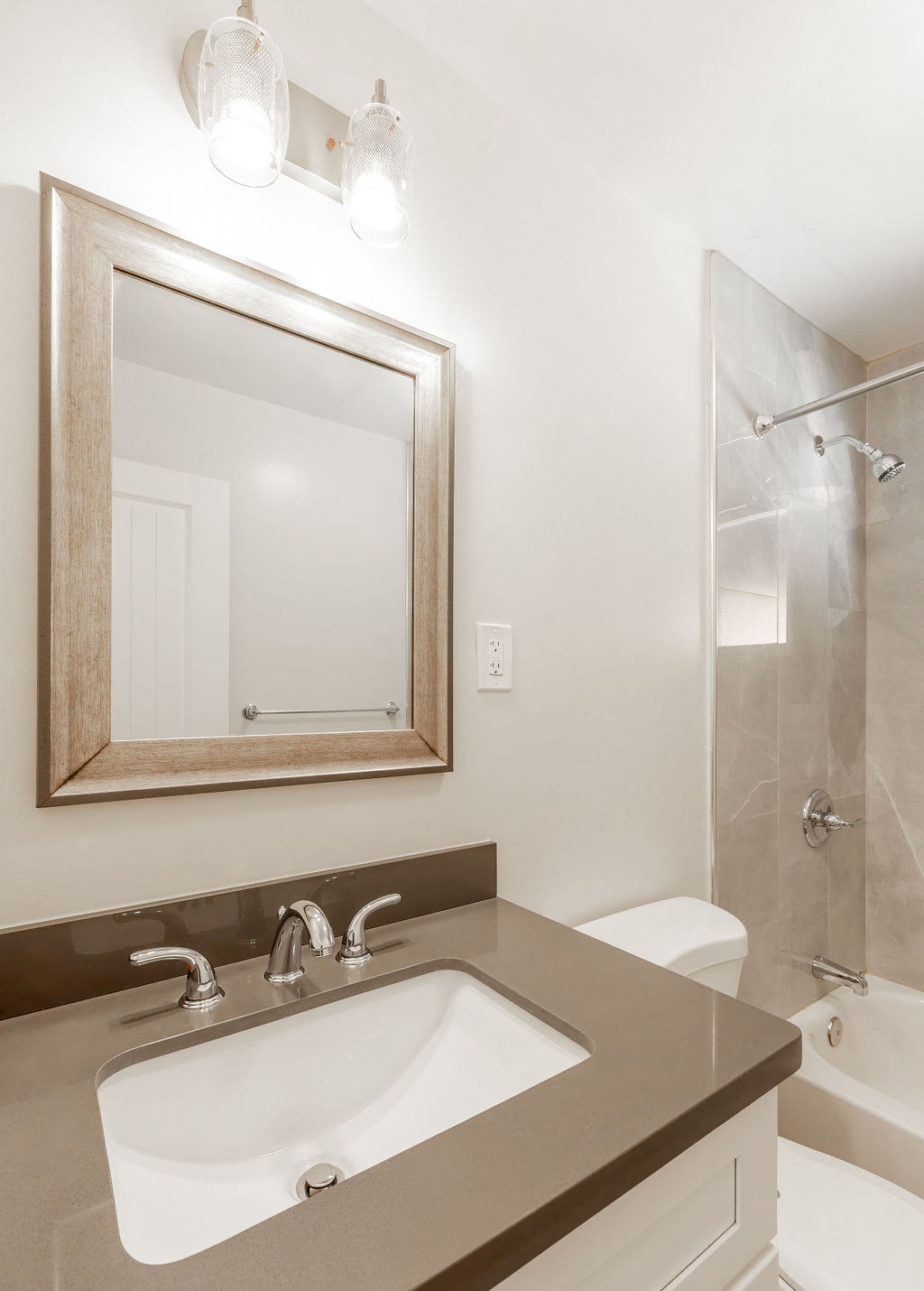A bathroom with a sink, mirror, and shower.