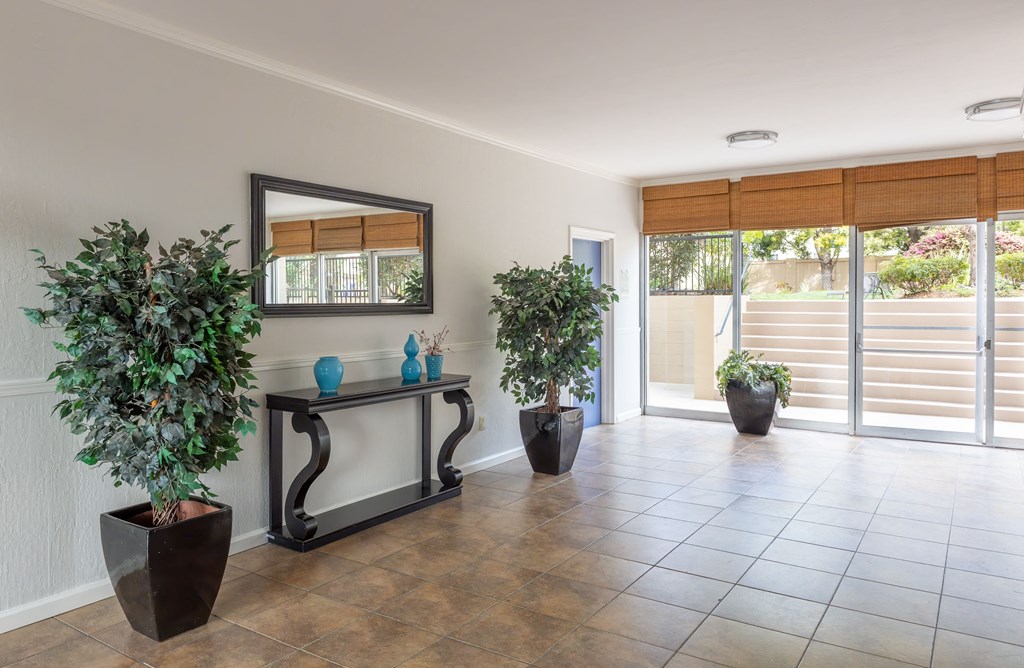 A room with a mirror, a bench, and potted plants.
