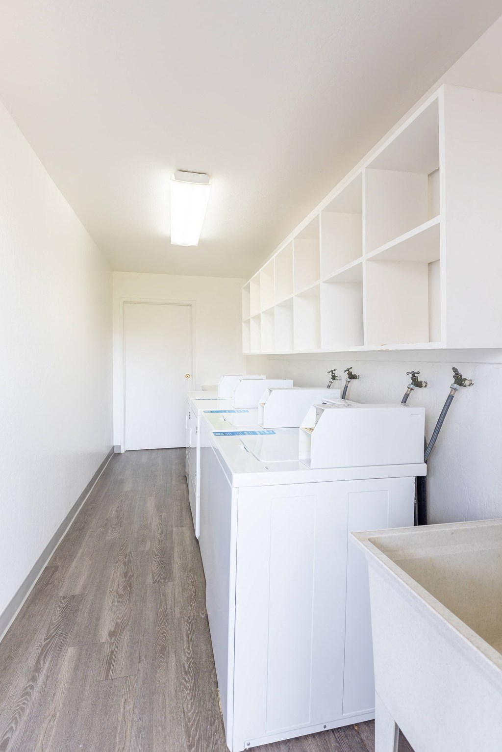 A white sink is in a white bathroom with wood floors.