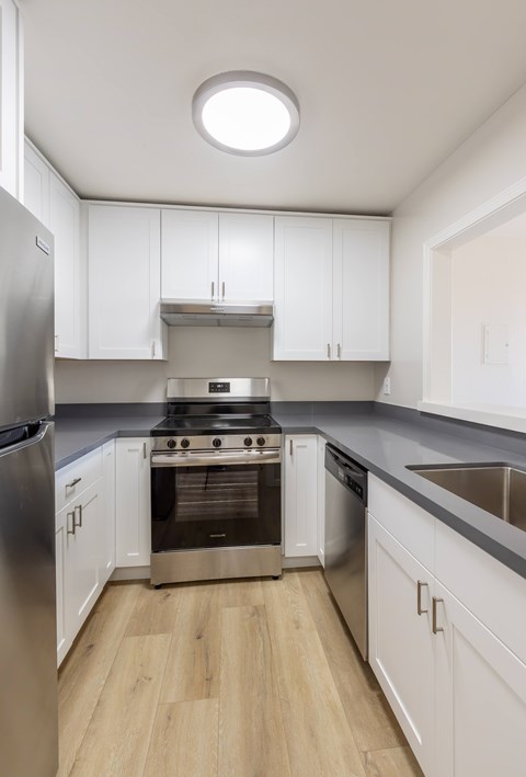 A modern kitchen with white cabinets and stainless steel appliances.