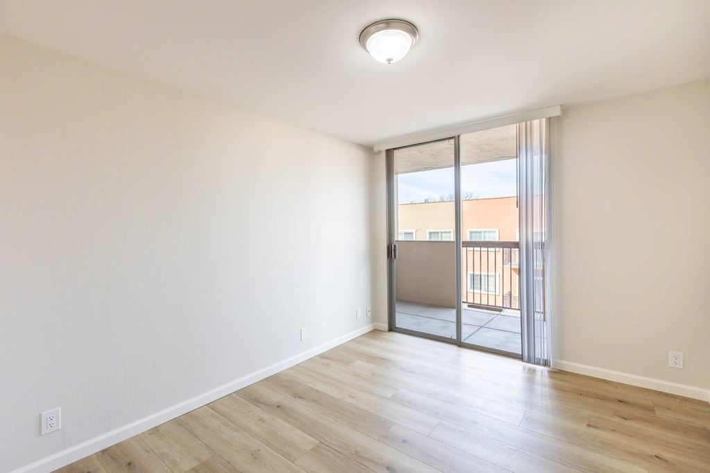 A room with a sliding glass door leading to a balcony.