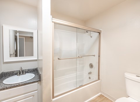 A white bathroom with a sink, toilet, and shower.